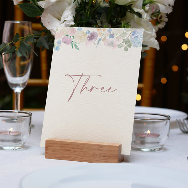 Table setting with a floral card and candles on a tablecloth.